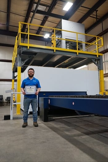 skylift crew member showing certification in front of laser cutting table